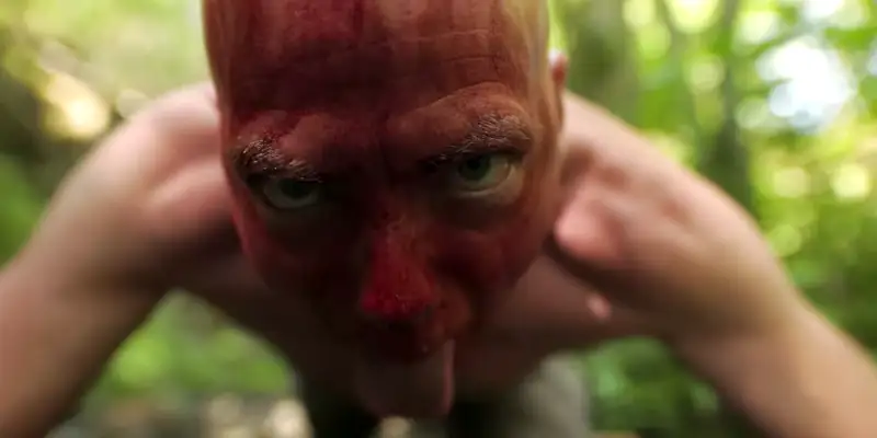 A scene from I'll See You in Disneyland showing Alex with his tongue out and blood over his face