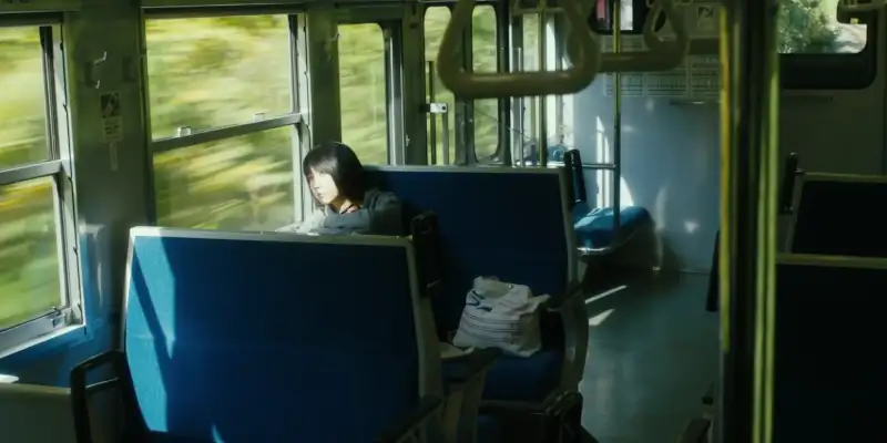 A scene from Mio on the Shore showing Mio alone on a train